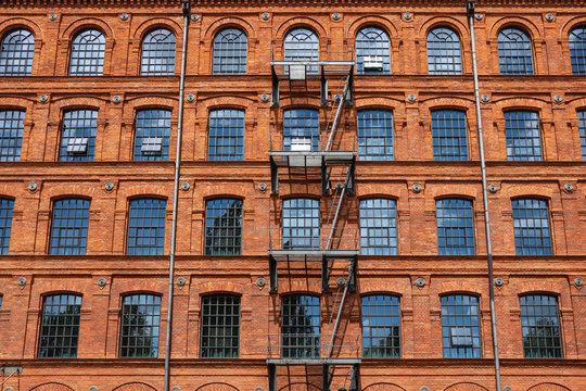 Red brick classic industrial building facade with multiple windows background.  - Powered by Adobe