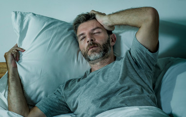 Fototapeta premium young sad and depressed man lying thoughtful and pensive on bed looking away feeling lost thinking suffering some problem in sadness emotion and depression concept
