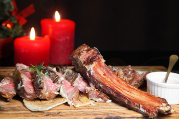 Rib eye steak on the New Year's table. Steak rib eye roast on a wooden board with sauce and salt. Beef steak on wooden plate.