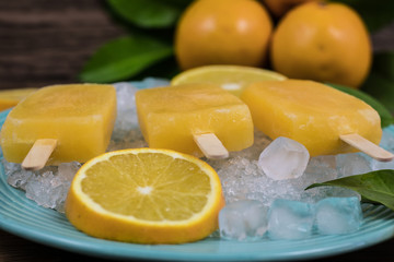 Orange flavor ice lollipops on wooden background