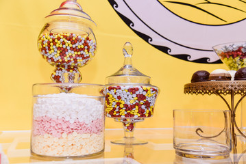 Candy bar ideas in a clear jars with yellow plain background multi color sweets for party celebration