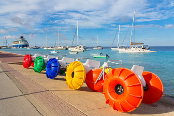 Pedal boats and sail boats by the sea with boulevard.