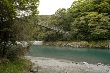 16th October 2019, New Zealand.People walking on hanging bridge over Makaroa River's Blue Pool in Mount Aspiring National Park.