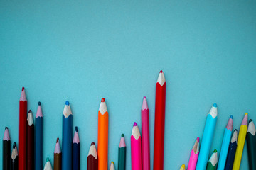 many multi-colored pencils on isolated on a blue background