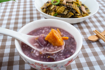 A plate of sauerkraut fried lean meat and a bowl of sweet potato porridge on the table