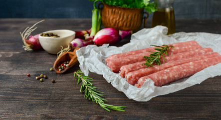 raw meat sausages for barbecue or hot dog. purple onions, salt and pepper, fresh oregano for marinade. grill  family dinner, healthy eating, keto diet food, meat recipe. Top view with copy space