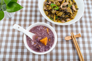 A plate of sauerkraut fried lean meat and a bowl of sweet potato porridge on the table
