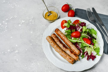 Healthy lunch grilled chicken sausages with tomato arugula salad. Top view copy space, chicken lunch recipe