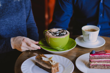 A couple in blue has breakfast in a cafe at a table with cups of coffee and slices of cake