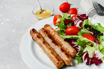 Healthy lunch grilled chicken sausages with tomato arugula salad. Top view copy space, chicken lunch recipe