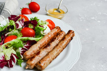Healthy lunch grilled chicken sausages with tomato arugula salad. Top view copy space, chicken lunch recipe