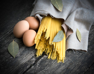 .raw pasta and eggs on a wooden background