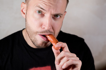 man eating a sausage, holding it with his hand