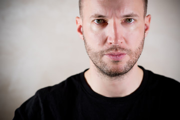 Obraz premium young handsome man with three-day stubble staring at the camera emotionlessly