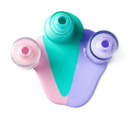 Pastel color spilled nail polish bottles over white