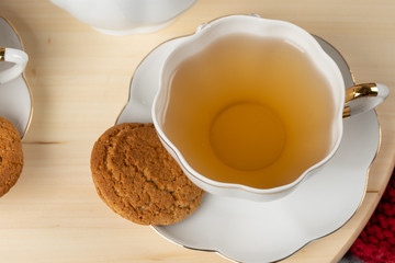 White porcelain cup of tea and oat cookies on a table