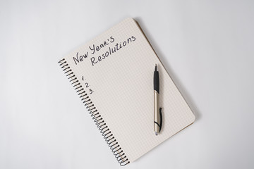 Phrase New Year's resolutions in the notebook and blank page, pen.