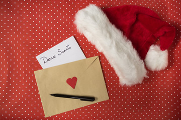 Letter for Santa in an envelope, pen. Santa hat. Red polka dot background