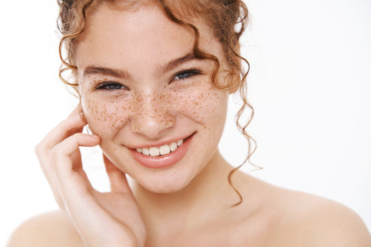 Headshot attractive sassy carefree redhead curly-haired girl naked freckled cheeks touch gently face smiling broadly like soft pure condition, apply skincare dermatology product, showering
