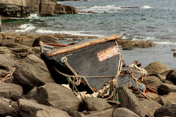 Vladivostok, Russia - September, 28, 2019: Wooden North Korean fishing boats thrown by a storm onto a rocky shore near Vladivostok.