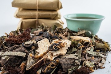 A pile of Chinese medicinal herbs and cooked soup on white background