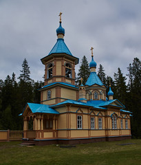 Fototapeta na wymiar Orthodox chapel.A lonely Orthodox chapel in a forest on the shore of Lake Ladoga on the island of Valaam. The hipped roof and cross on the dome are visible. Russia, Karelia