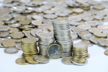 Gestapelte Euro-Münzen vor ganz viel Bargeld