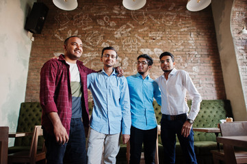 Group of four south asian men's posed at business meeting in cafe. Indians having conversation.