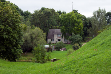Rural Latvia, view across park and stream with village house