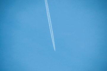  plane at high altitude leaving wake in its wake over blue sky