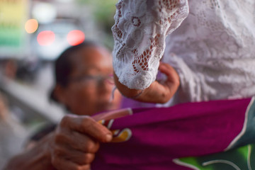 Balinese woman wrapping sarong around young tourist girl