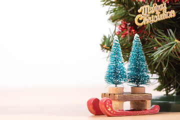 Decorated cute Christmas tree on a wooden floor with white background and toys, blank for festive design concept, close up.