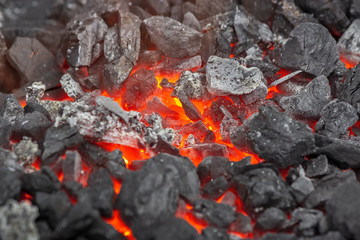 Embers glow in a forge or bonfire. Fire, heat, coal and ash with flying sparks.