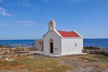 Fototapeta na wymiar A small Church with bell on the edge of the stonecoast of the Aegean sea in Greece