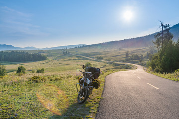 Fototapeta na wymiar Touring motorcycle parking on asphalt road passing through grassland with sunbeams
