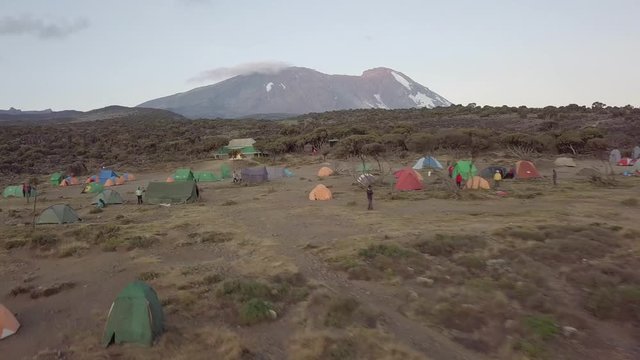 Aerial backwards dolly, flying over the Shira Basecamp, Kibo Peak in the background.