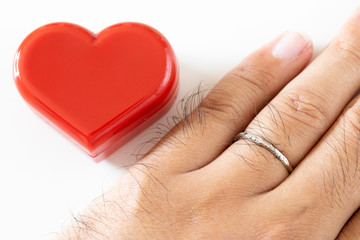 結婚指輪を身に着けた男性の手とハートの置物