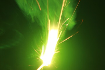 Green smoke sparkler sparkling on dark background with some green color smoke on the deepavali ...