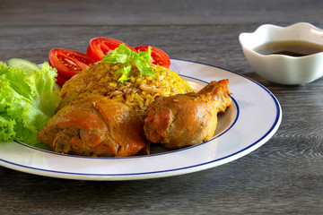 Chicken Biryani on white dish with green sauce (Muslim yellow rice with chicken) on brown wooden background