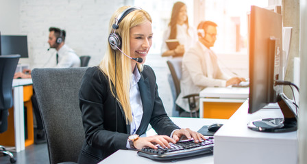 Portrait of young customer service executive in headset working on computer in call center