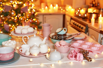 Christmas decor in kitchen. Christmas dishes and sweets. Bright interior of New Year's kitchen. New year card template. The kitchen is white and pink colors. Christmas tree in the kitchen