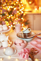 Christmas decor in kitchen. Christmas dishes and sweets. Bright interior of New Year's kitchen. New year card template. The kitchen is white and pink colors. Christmas tree in the kitchen