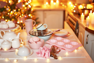 Christmas decor in kitchen. Christmas dishes and sweets. Bright interior of New Year's kitchen. New year card template. The kitchen is white and pink colors. Christmas tree in the kitchen