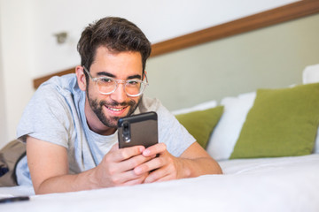 Young man typing a message in bed