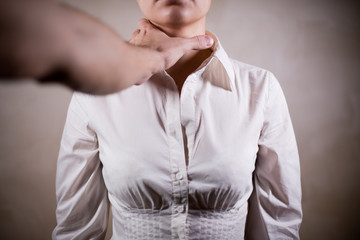 male hand reaches for the throat of a girl in a white shirt