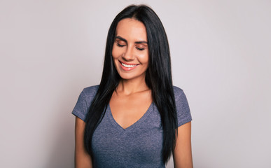 Perfect smile. Close-up photo of a cute girl with long jet-black hair, who is posing with her eyes closed and smiles broadly.