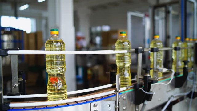 Bottles of oil moving on the conveyor line. Production of sunflower oil in a factory. Interior of modern natural oil factory.