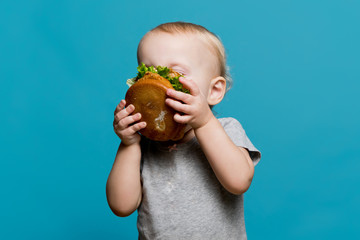 little girl enthusiastically bites or sniffs a burger the size of her face