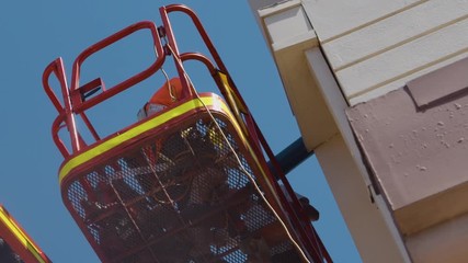 A low angle and a close-up of tradesmen upon a boom lift