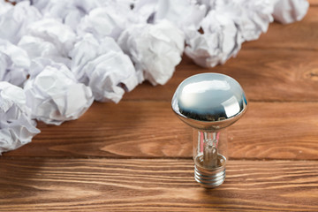 Ideological concept with wastepaper light bulb on wooden table